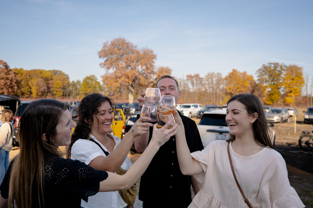 Four friends clinking their glasses of wine at the Tasting Room during Tanglewood Winery's Fall Festival.